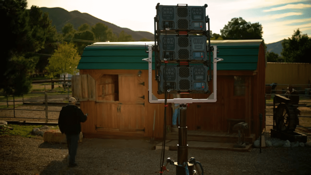Three Aputure NOVA 9° LED panel lights stacked in a Triple-Yoke array on a heavy-duty stand to simulate 1,500W of high-intensity sunlight outside a film location.
