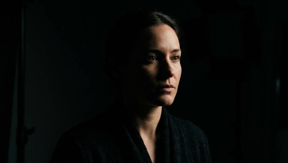 A dramatic, dark cinematic portrait of a woman's face used to illustrate the philosophy of 3-point studio lighting as a recreation of natural sunlight and deep shadows.