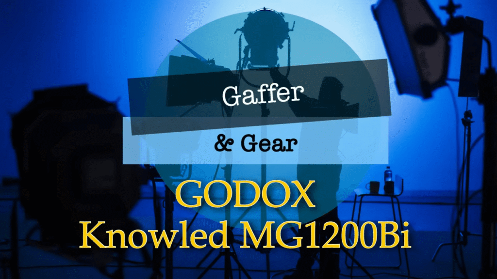 A close-up view of a Godox LED video light resting on a studio table, surrounded by professional lighting equipment and diffusion softboxes in a working photo studio.