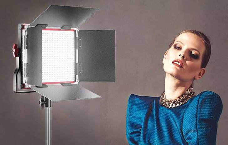 Professional LED video lighting panel with barn doors, positioned to illuminate a model in a studio setting, demonstrating its use in portrait and video production.